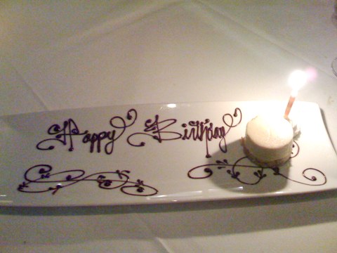 happy happy joy joy a tiny disc of custard on a large dish upon which 'happy birthday' is written with chocolate